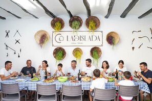 A family dining at a restaurant with a checkered tablecloth, hanging decorations, and a sign above the table.