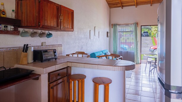 Una cocina con armarios de madera, una isla integrada con taburetes, un tostador y un refrigerador.