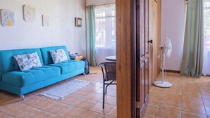 Un salón con un sofá color turquesa, una mesita y un ventilador.
