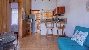 Una cocina compacta con armarios de madera, un refrigerador y un comedor con una mesa redonda y sillas.