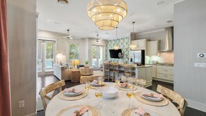 A dining area with a round table set for six, surrounded by wooden chairs. - Golf Cart, Bikes, Game Room, Walk to Big Chill, Minutes from Seaside & Rosemary (Santa Rosa Beach)