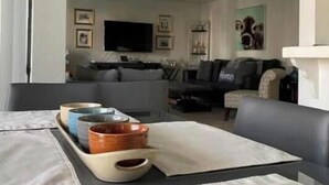 Un salon moderne avec un canapé, une table basse agrémentée de bols décoratifs et un téléviseur à écran plat fixé au mur.