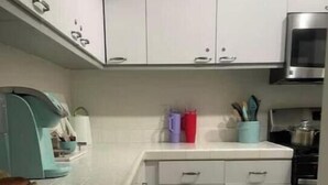 Une cuisine avec des meubles blancs, un four à micro-ondes et une cuisinière.