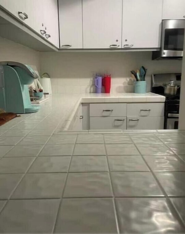 Una cocina con armarios blancos, un microondas y una estufa.