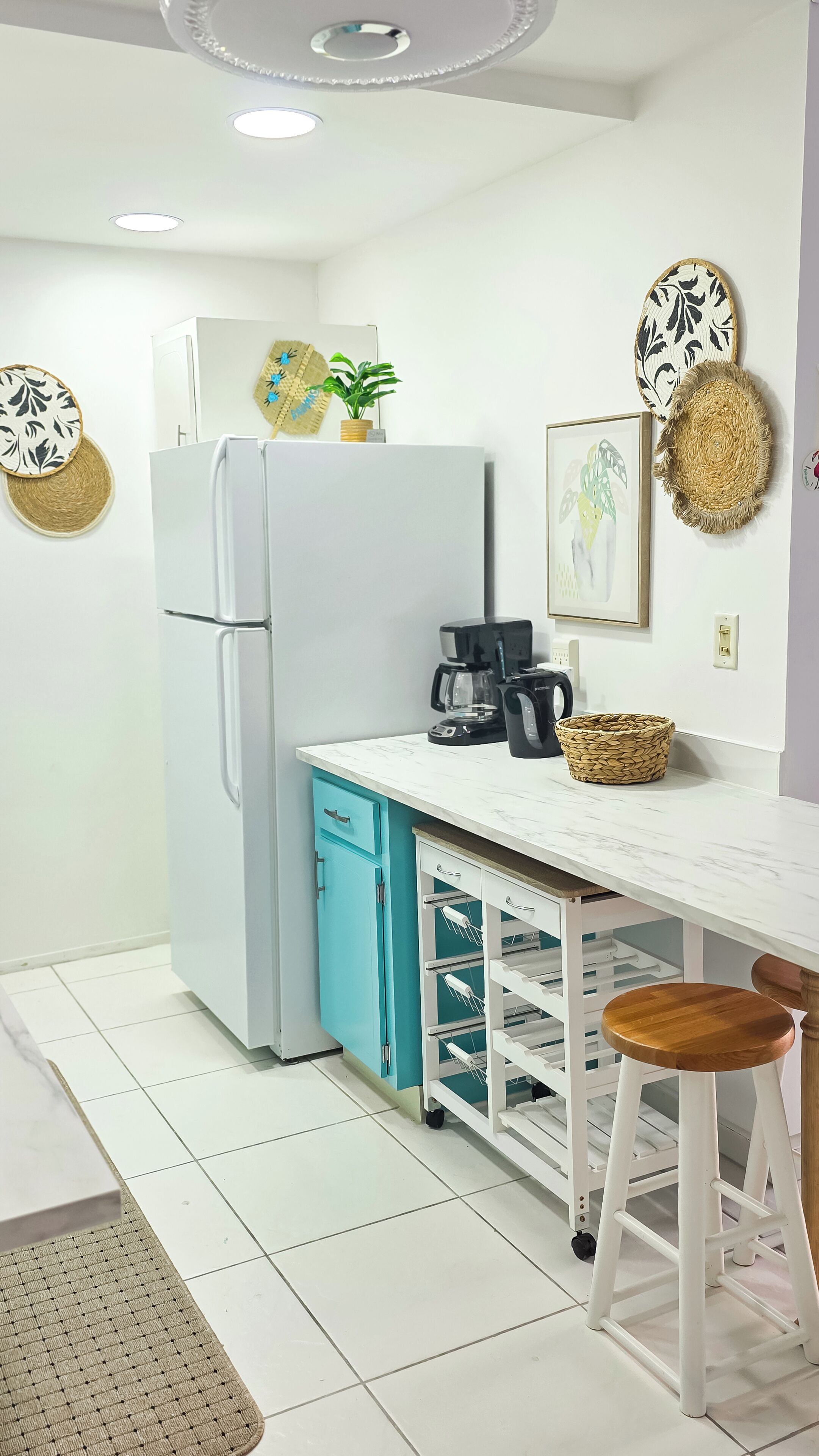 A modern kitchen with a white refrigerator, a coffee maker, and a blue cabinet.