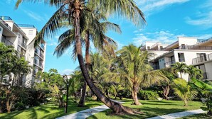 Un barrio residencial con edificios de varios pisos, palmeras y un césped cuidado.