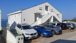 Un edificio moderno con fachada blanca, plazas de aparcamiento y vistas despejadas al mar.