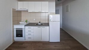 A compact kitchen with white cabinetry, a built-in oven, a sink, and a refrigerator. - Lovely apartment in Rtina with WiFi (Rtina)