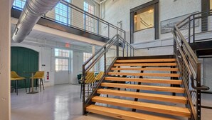Un intérieur spacieux avec un escalier central en bois, de hauts plafonds et de grandes fenêtres qui laissent entrer la lumière naturelle.