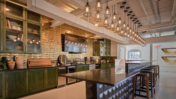 Une cuisine moderne dotée d’un îlot central, de meubles de couleur verte et de luminaires suspendus.