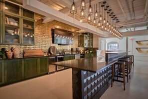 Een moderne keuken met een centraal eiland, groene kasten en hanglampen.