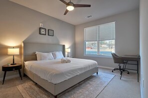 A bedroom with a bed, two bedside tables, a desk, and a window with blinds. - Stylish, Cozy 2BD Apt Near DT Clayton | Pool | Gym (Clayton)