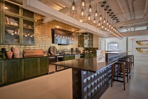 A modern kitchen with a large island, green cabinets, and pendant lighting. - Stylish, Cozy 2BD Apt Near DT Clayton | Pool | Gym (Clayton)