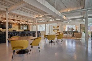 A modern interior with a bar area, seating with yellow chairs, and a large table. - Stylish, Cozy 2BD Apt Near DT Clayton | Pool | Gym (Clayton)