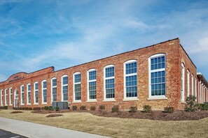 A long brick building with multiple arched windows and a flat roof. - Stylish, Cozy 2BD Apt Near DT Clayton | Pool | Gym (Clayton)