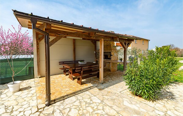 A covered outdoor area with a picnic table and a stone-tiled floor. - Beautiful apartment in Pula (Pula)