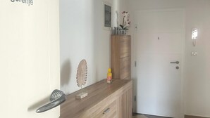 A hallway with a wooden counter, a door, and a small shelf with decorative items.