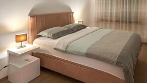 A neatly made bed with a wooden headboard, two bedside lamps, and a white nightstand.