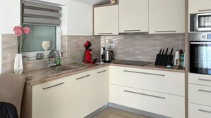A modern kitchen with white cabinets, a stainless steel sink, and a built-in oven.