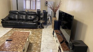 A living room with a black leather sofa, a coffee table, a TV, and a fireplace.