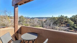Un balcón con vistas a un paisaje montañoso, una mesa y dos sillas.