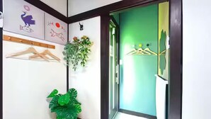 Passadís amb una porta verda, una planta penjant a la paret i una pilona de fusta.