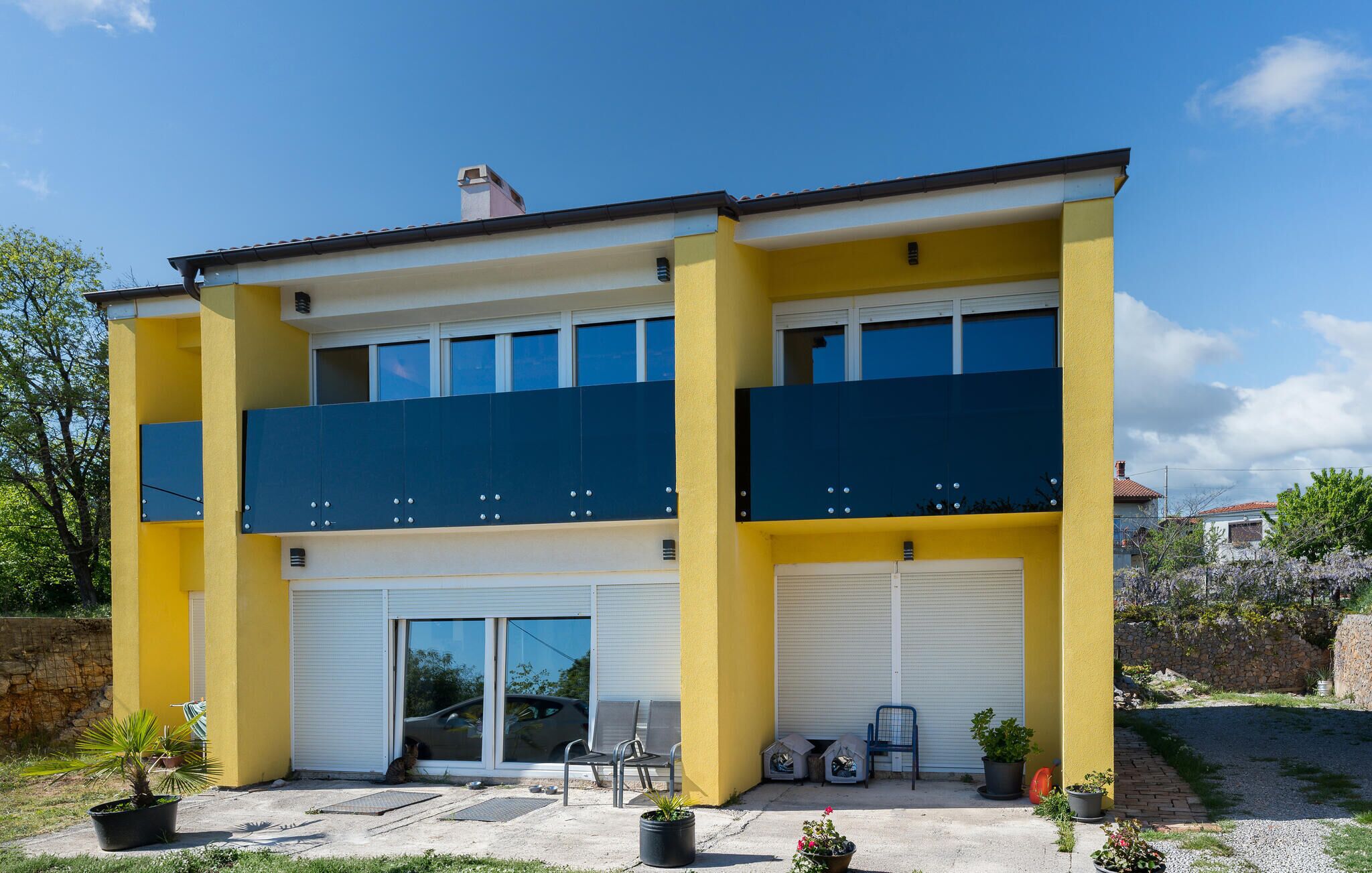 Un bâtiment à deux étages avec une façade jaune, de grandes fenêtres et une porte de garage.