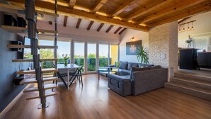 Un salon moderne avec un plafond en bois, un canapé, une table à manger et un escalier menant à un niveau supérieur.