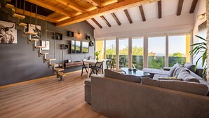 Un salon moderne avec un plafond en bois, une grande télévision, un coin repas et un canapé.
