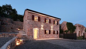 A stone house with a sloped roof, a wooden door, and three windows with shutters. - Awesome home in Prizna (Prizna)