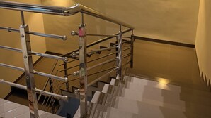 A modern staircase with a metal handrail and a wall-mounted light fixture. - Hotel vimlayatan (Ujjain)