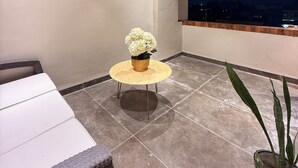 A balcony with a round table, a ceiling fan, and a potted plant. - Hotel vimlayatan (Ujjain)
