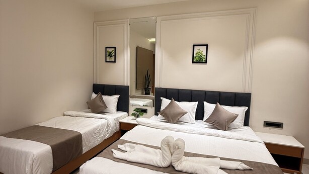 A hotel room with two beds, a ceiling fan, and a large mirror. - Hotel vimlayatan (Ujjain)