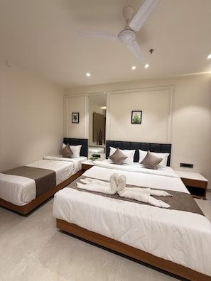A hotel room with two beds, a ceiling fan, and a large mirror. - Hotel vimlayatan (Ujjain)