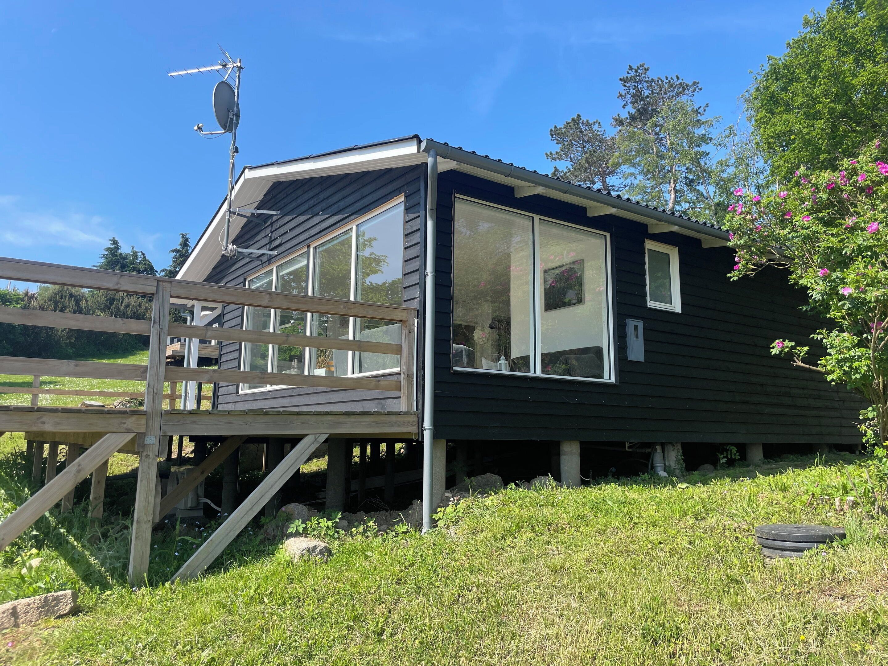 A house with a large window, a wooden deck, and a satellite dish.