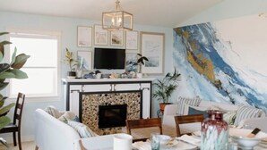 A living room with a fireplace, a television, and a large abstract painting on the wall. - Fun for the whole Family with a beautiful view! (French River)