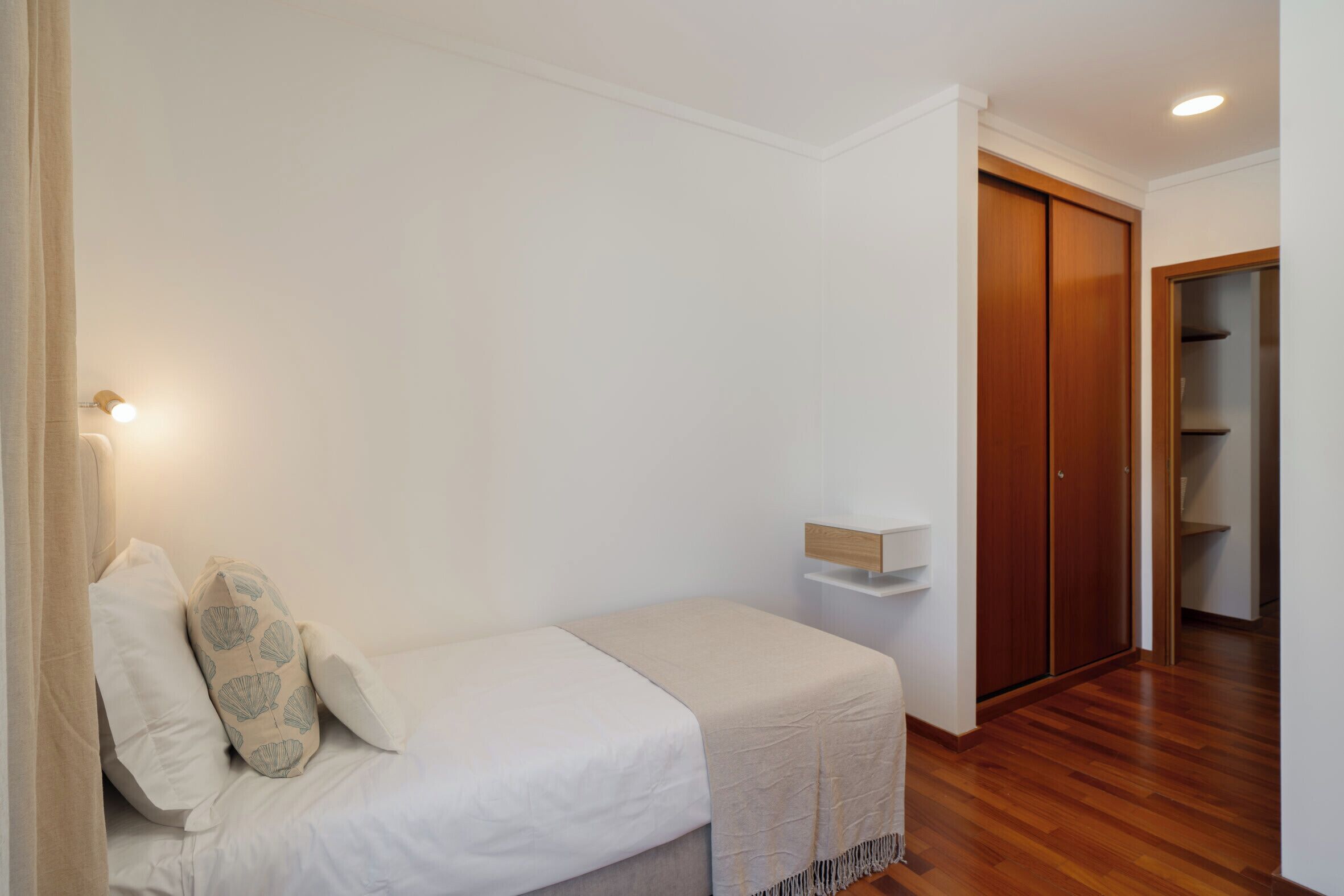 Ein Schlafzimmer mit Bett, Nachttisch, Holzschrank und Regaleinheit.