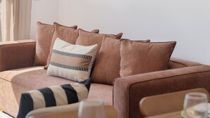 A modern living room with a sofa, a dining table set with plates and glasses, and a wall art piece. - Wings Apartment II – With Balcony in Santa Cruz (Santa Cruz)