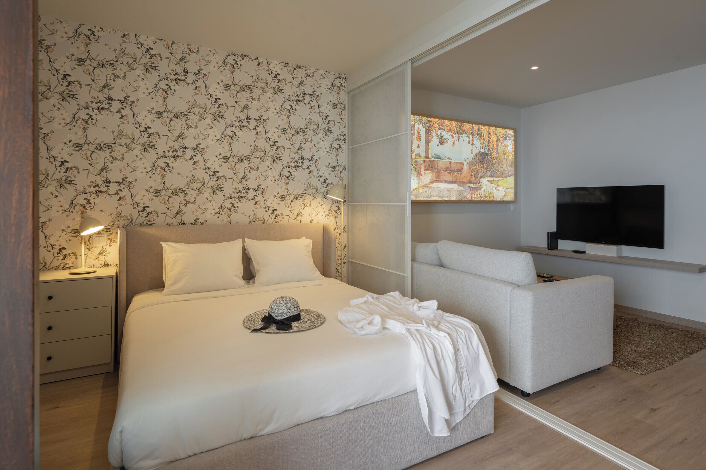 Ett modernt hotellrum med en stor säng, en soffa, en platt-TV och en tavla på väggen.