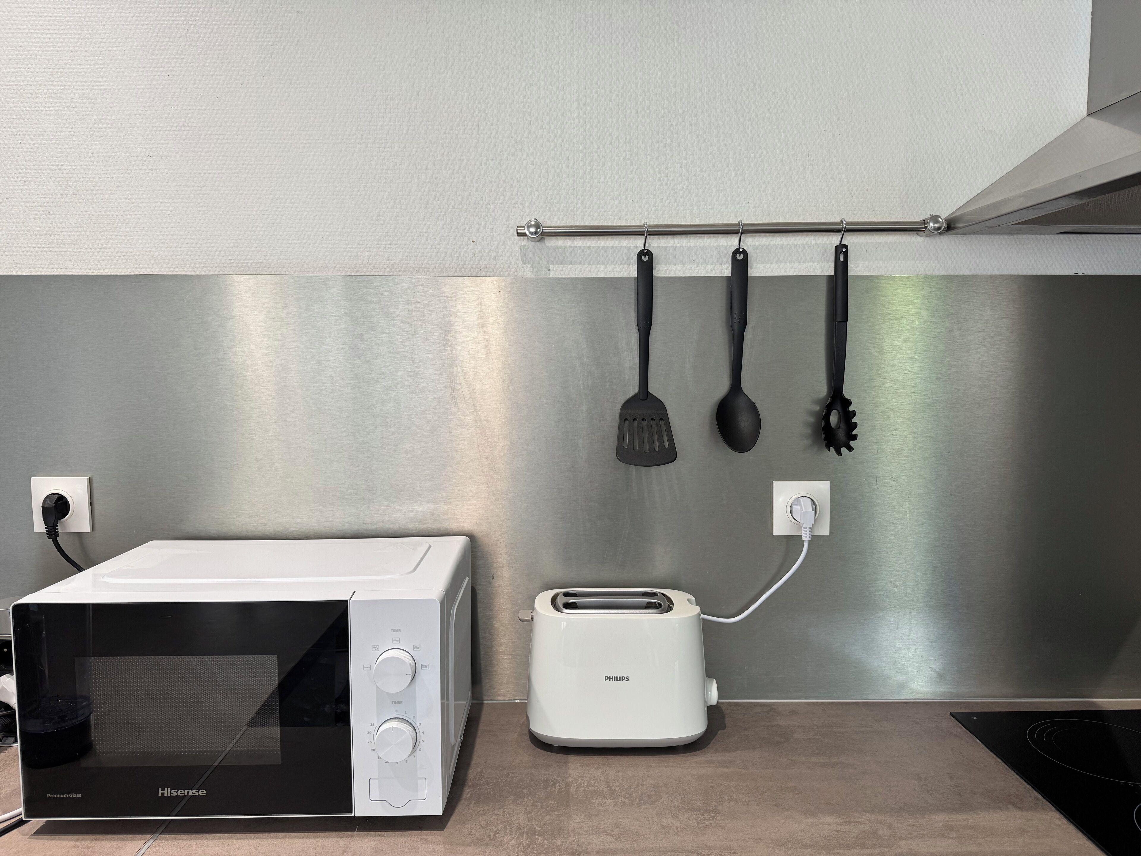 Een keuken met een Hisense magnetron, een Philips broodrooster en een achterwand van roestvrij staal.