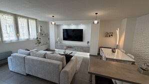 Un salon moderne avec un canapé, un téléviseur et un coin repas.