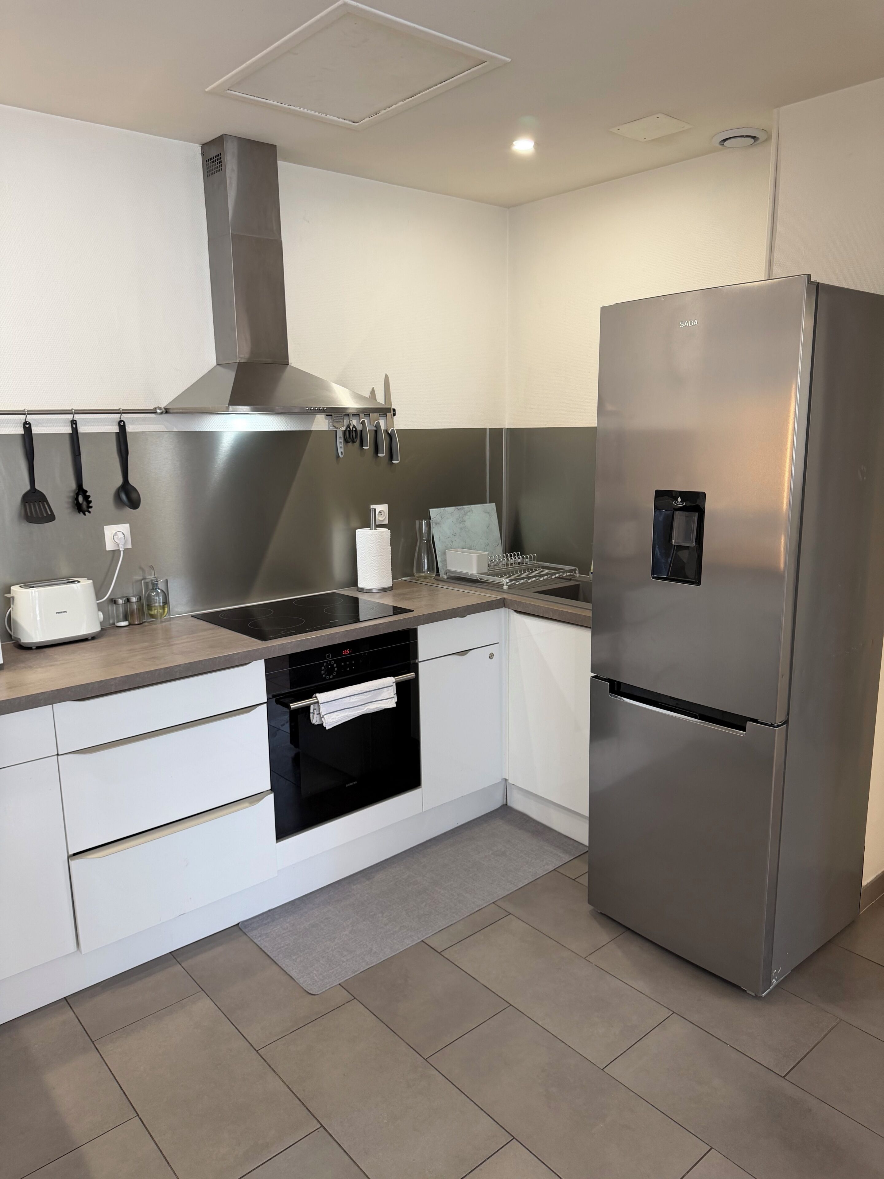 Una cocina moderna con un refrigerador de acero inoxidable, un horno empotrado y una estufa.