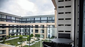 A modern building with a glass balcony overlooking a courtyard with greenery and a pool. - Imperial Suite | 1BR Pool-View Unit, Cantonments Close to KIA & American Embassy (Accra)