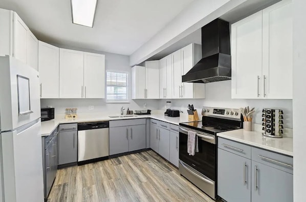 Una cocina moderna con armarios blancos, electrodomésticos de acero inoxidable y suelo con estampado de madera.