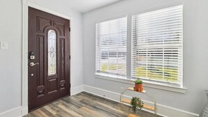 A room with a dark brown door, white trim, and a window with white blinds.