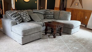 A living room with a sectional sofa, a coffee table, and patterned rugs. - Charming 2-bedroom home in Hackensack. Enjoy during the summer and winter. (Hackensack)