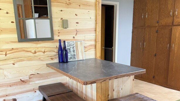 A wooden interior with a kitchen counter, stools, and a cabinet. - Charming 2-bedroom home in Hackensack. Enjoy during the summer and winter. (Hackensack)