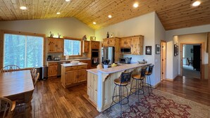 Une cuisine spacieuse avec des meubles en bois, un îlot central doté de tabourets de bar et une grande fenêtre qui laisse entrer la lumière naturelle.