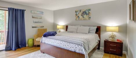 A bedroom with a bed, two bedside tables, a chair, and a window with curtains.