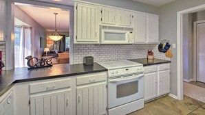 A kitchen with white cabinets, a microwave, a stove, and a tiled backsplash.